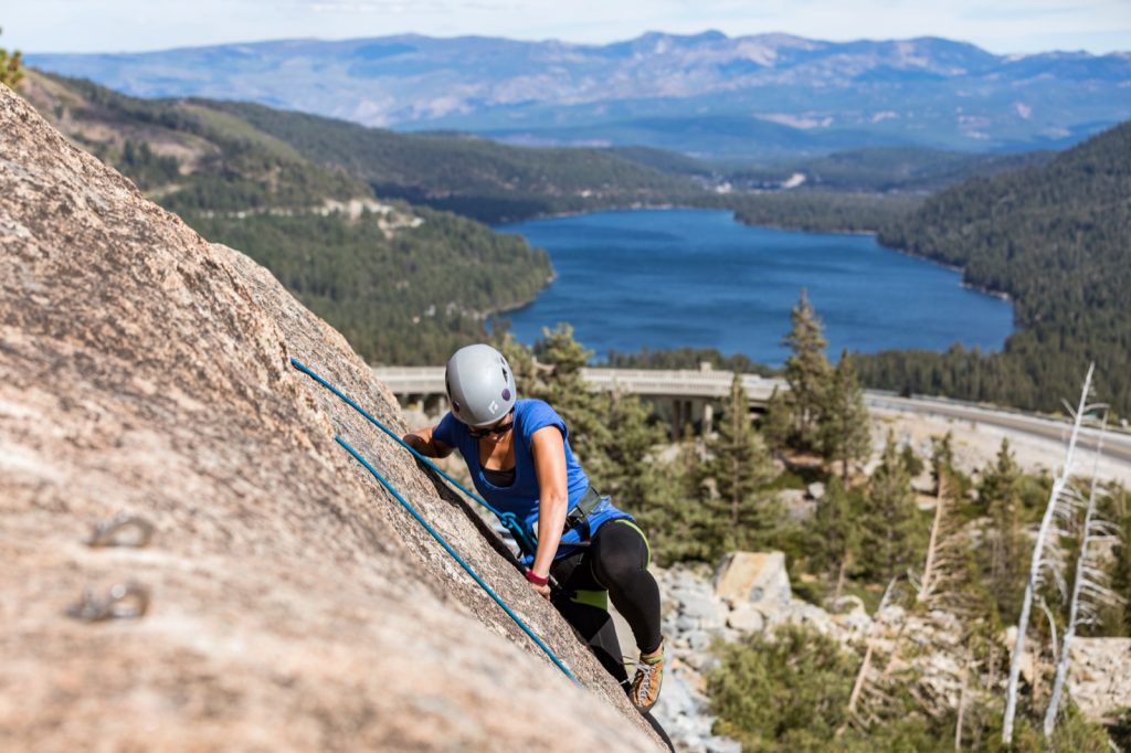 woman climbing at Donner Summit with bridge and Donner Lake in the background