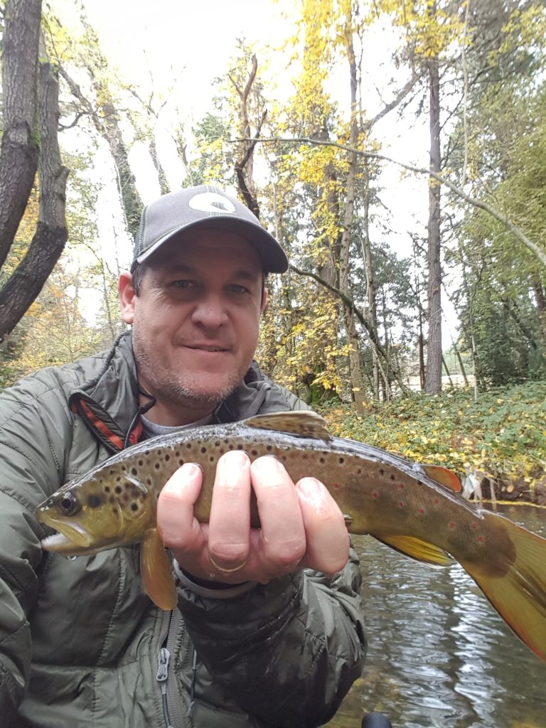 man holding a caught trout from a river