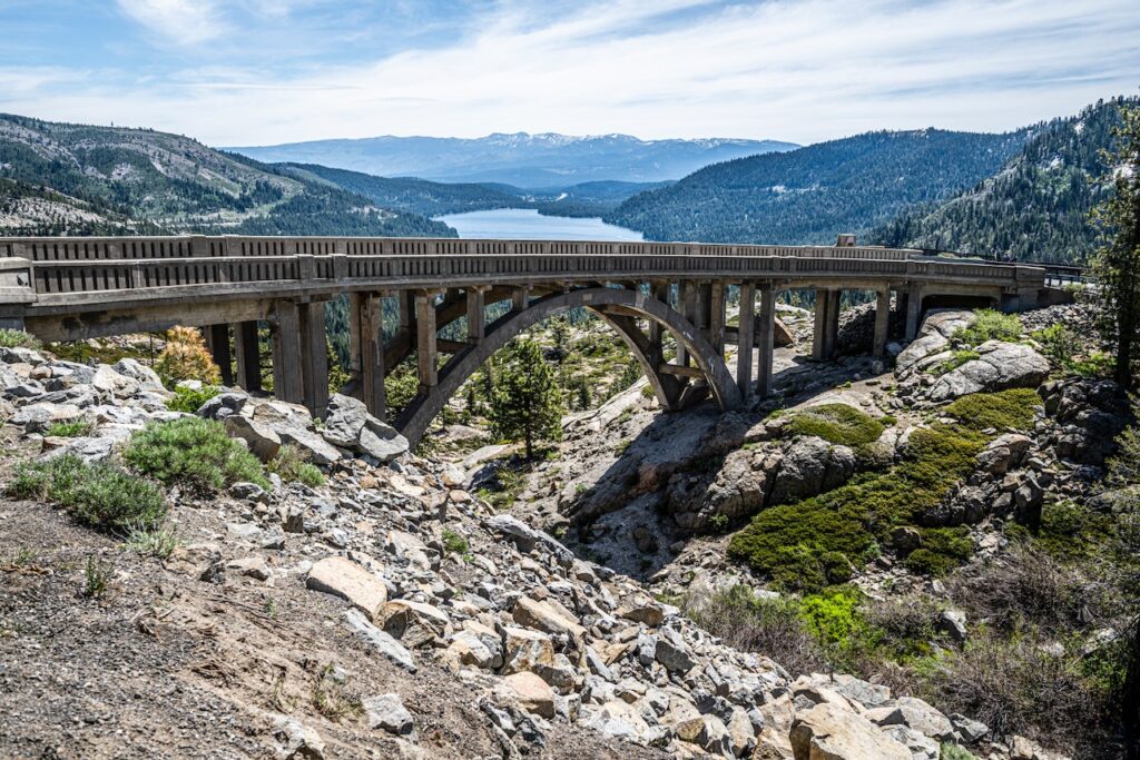 Donner Memorial Bridge or the Rainbow Bridge in summer with granite outcroppings below it and Donner Lake in the distance