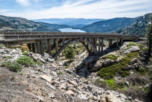 Donner Memorial Bridge or the Rainbow Bridge in summer with granite outcroppings below it and Donner Lake in the distance