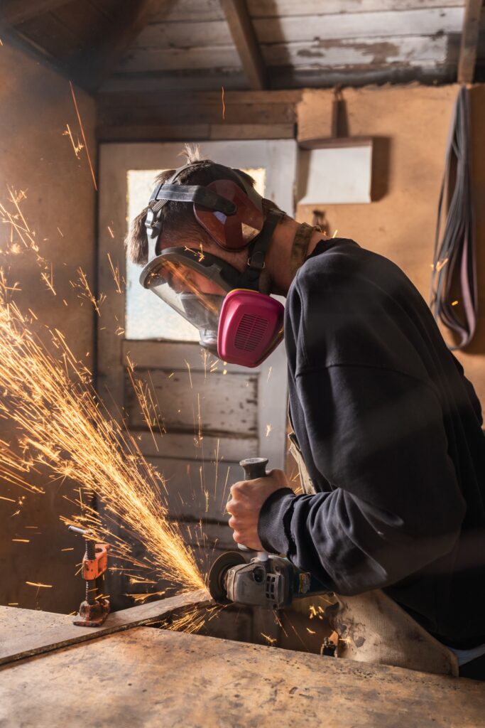 Everett Noel using metal grinder in his shop.