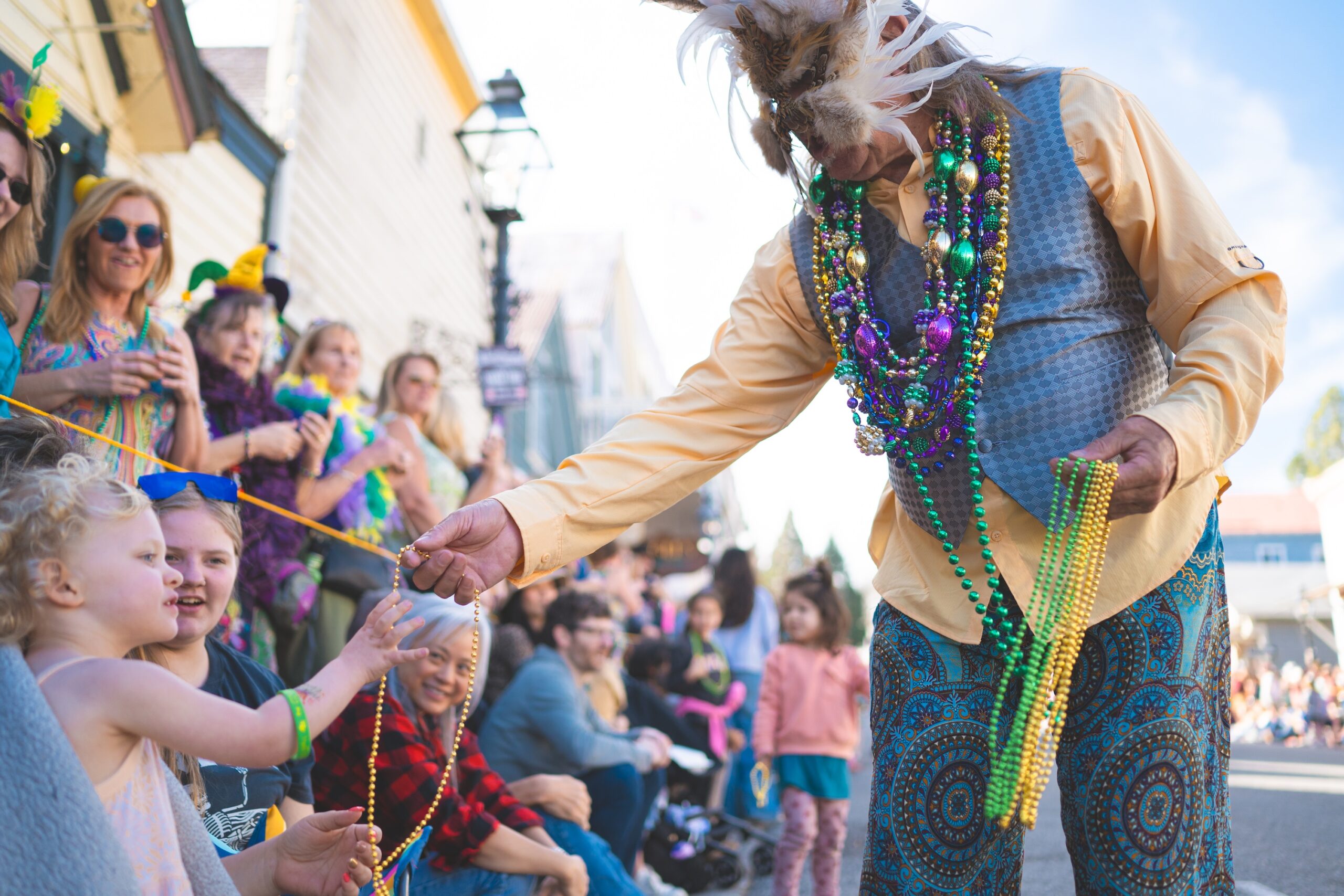Parade goer giving beads to a kid in the Nevada City Mardi Gras parade
